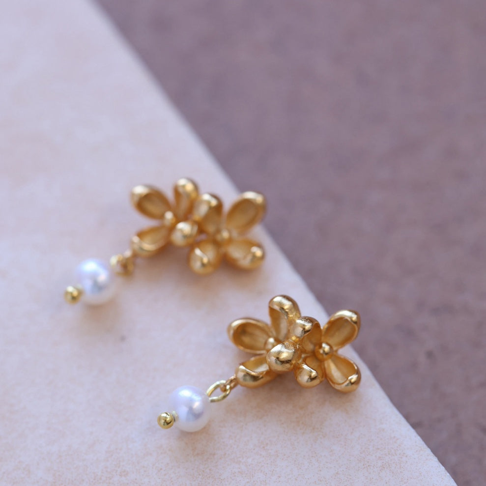 Close-up shot showing the matte texture of 18k gold flower petals and the luster of a natural freshwater pearl -4