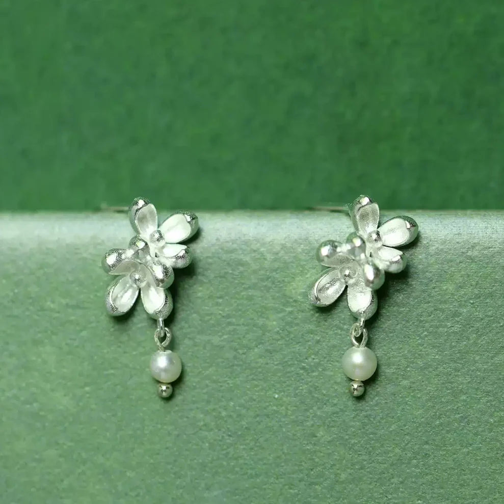 Close-up shot showing the matte texture of silver flower petals and the luster of a natural freshwater pearl -3