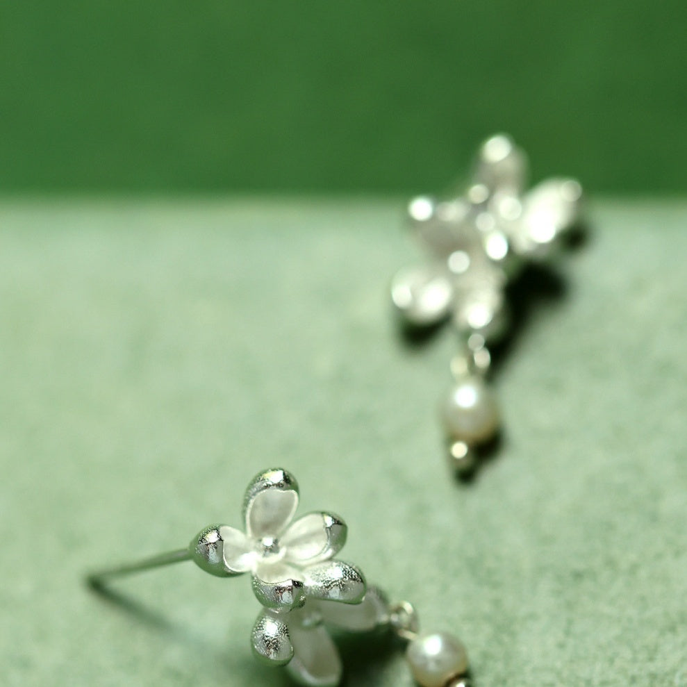 Close-up shot showing the matte texture of silver flower petals and the luster of a natural freshwater pearl -1