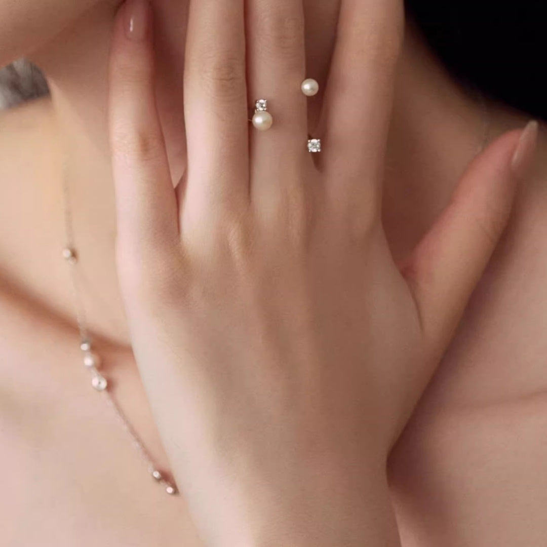 Close-up of a hand resting on the neck, featuring an adjustable floating pearl ring and a matching pearl necklace, ideal for non-traditional wedding jewelry.