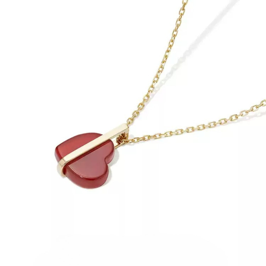Necklace with a red heart-shaped pendant and gold chain on a white background