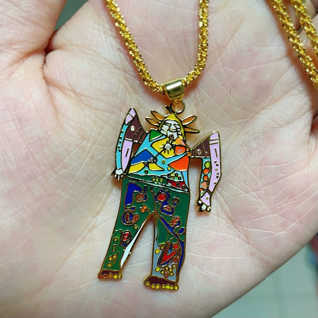 Colorful angel pendant on a gold chain held in a hand.
