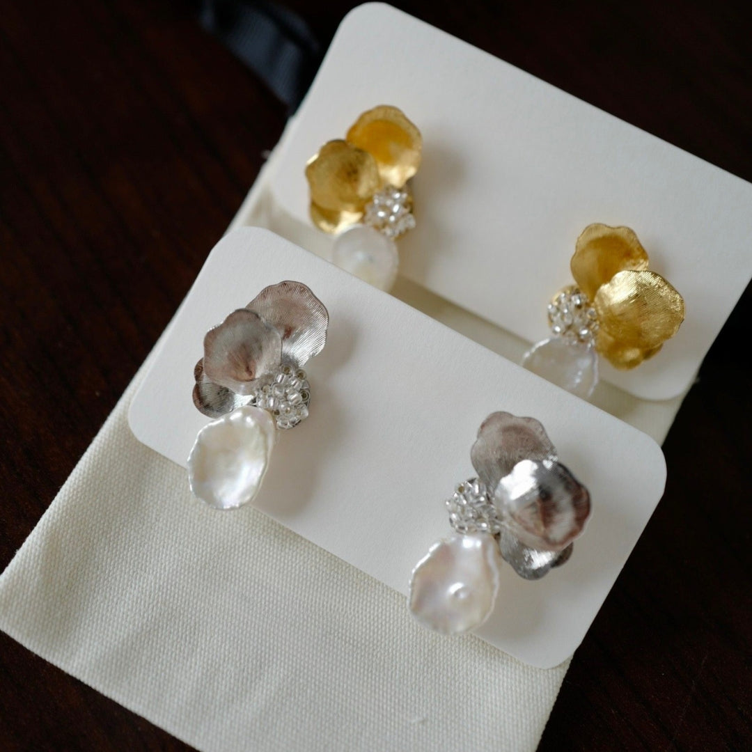 Pair of earrings with gold and silver flower petal on a white card.