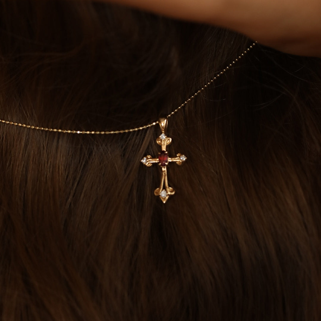 18k Gold cross pendant with ruby gemstone on a chain.