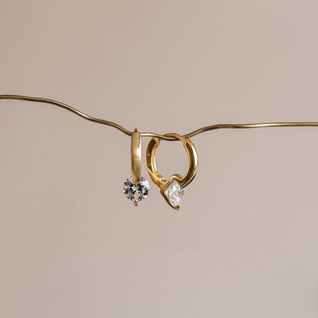Gold hoop earrings with embedded diamonds on a beige background