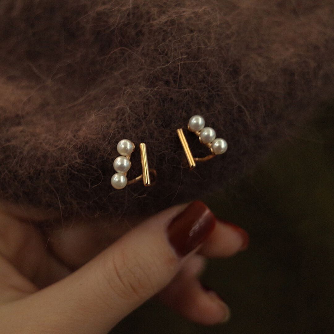 Close-up of gold bar pearl earrings featuring Tiny pearl studs arranged in a trio on Gold bar earring studs, perfect as Minimalist Wedding Earrings and Dainty elegant earrings for everyday wear.