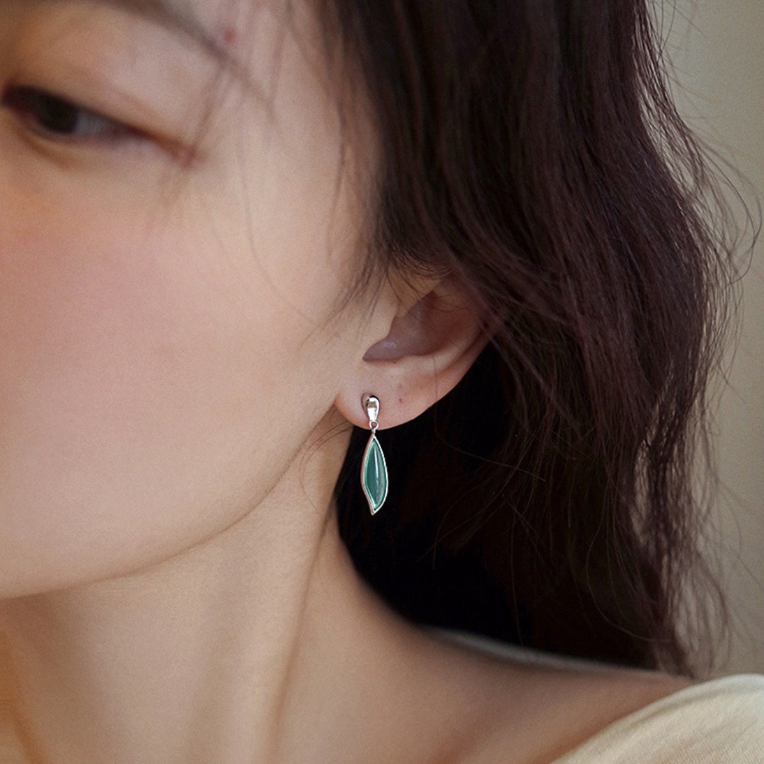 Close-up of a person wearing a green leaf earring.