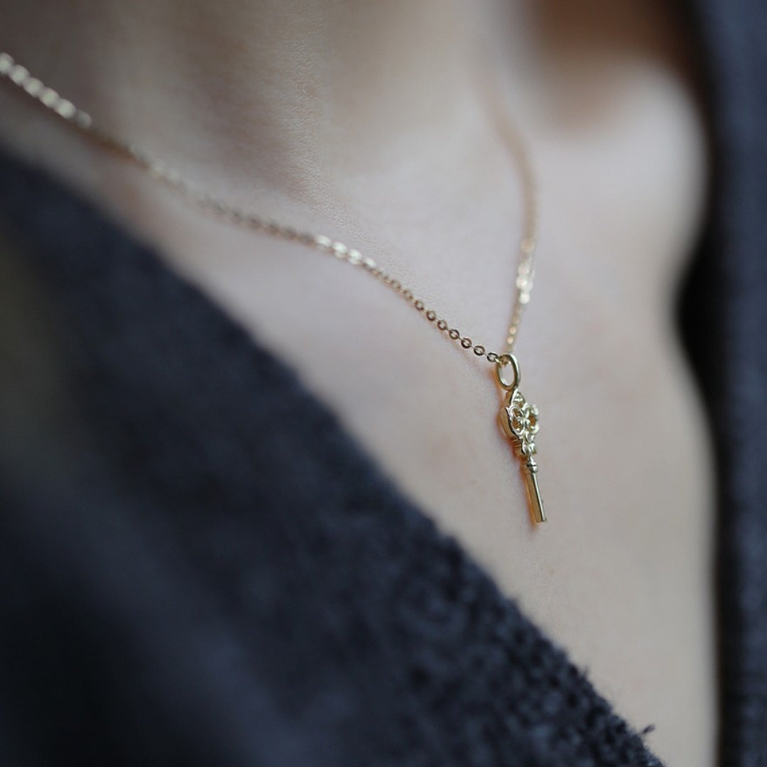14k gold necklace with a key pendant worn by a person