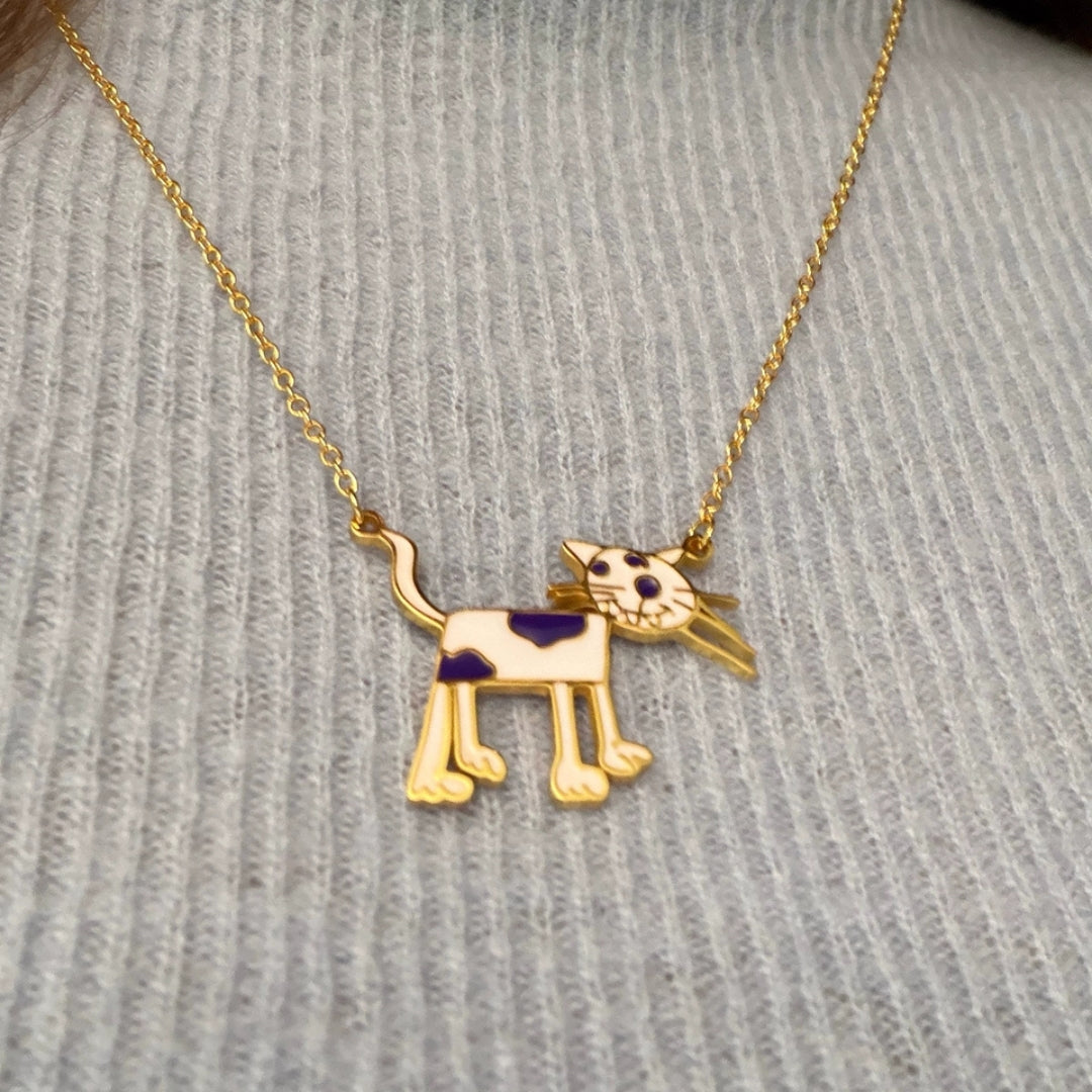 Gold necklace with a dog-shaped pendant on a textured gray surface