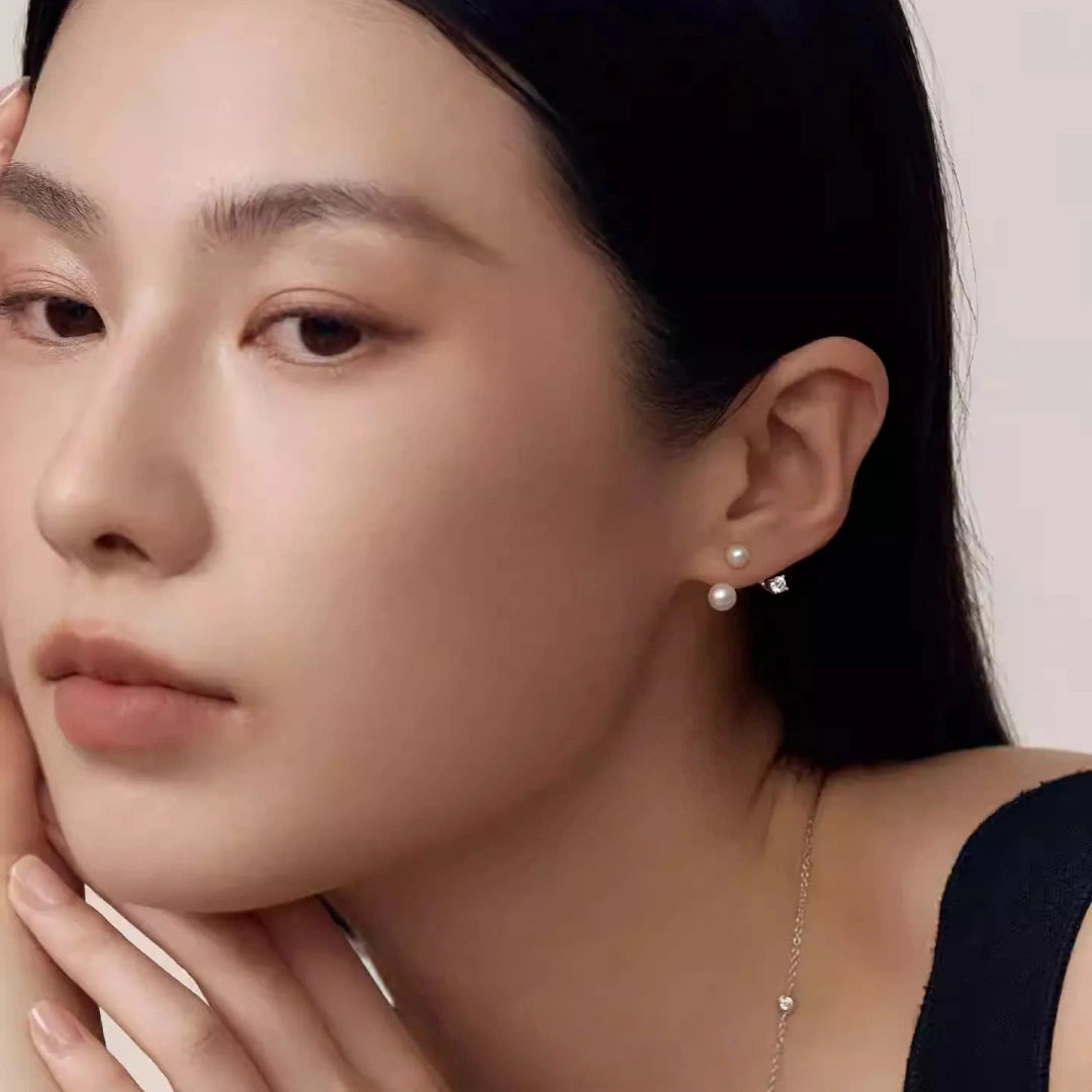 A woman touching her face, highlighting the vertical line of a geometric pearl ring, a sophisticated accessory for minimalist wedding photography.