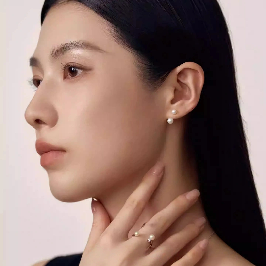 A close-up side profile of a woman wearing modern S925 sterling silver wrap-around pearl earrings with cubic zirconia accents, perfect for minimalist bridal jewelry.