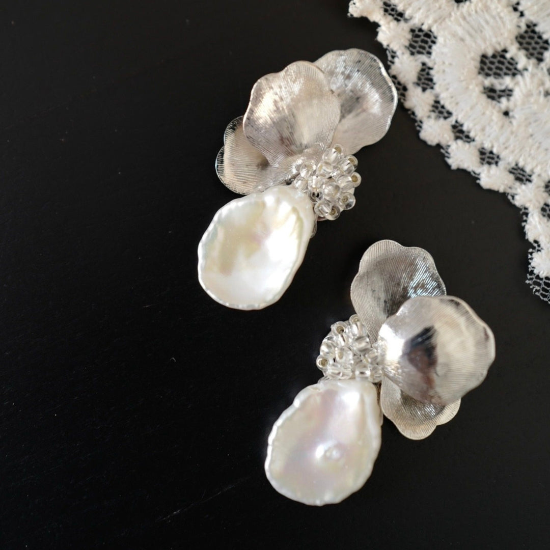 Pearl earrings with silver accents on a black background