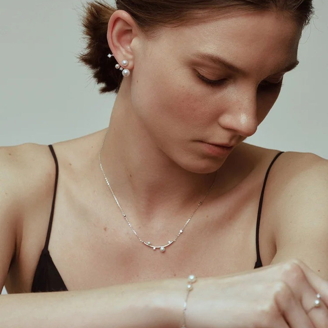 A woman wearing a pearl and diamond necklace.