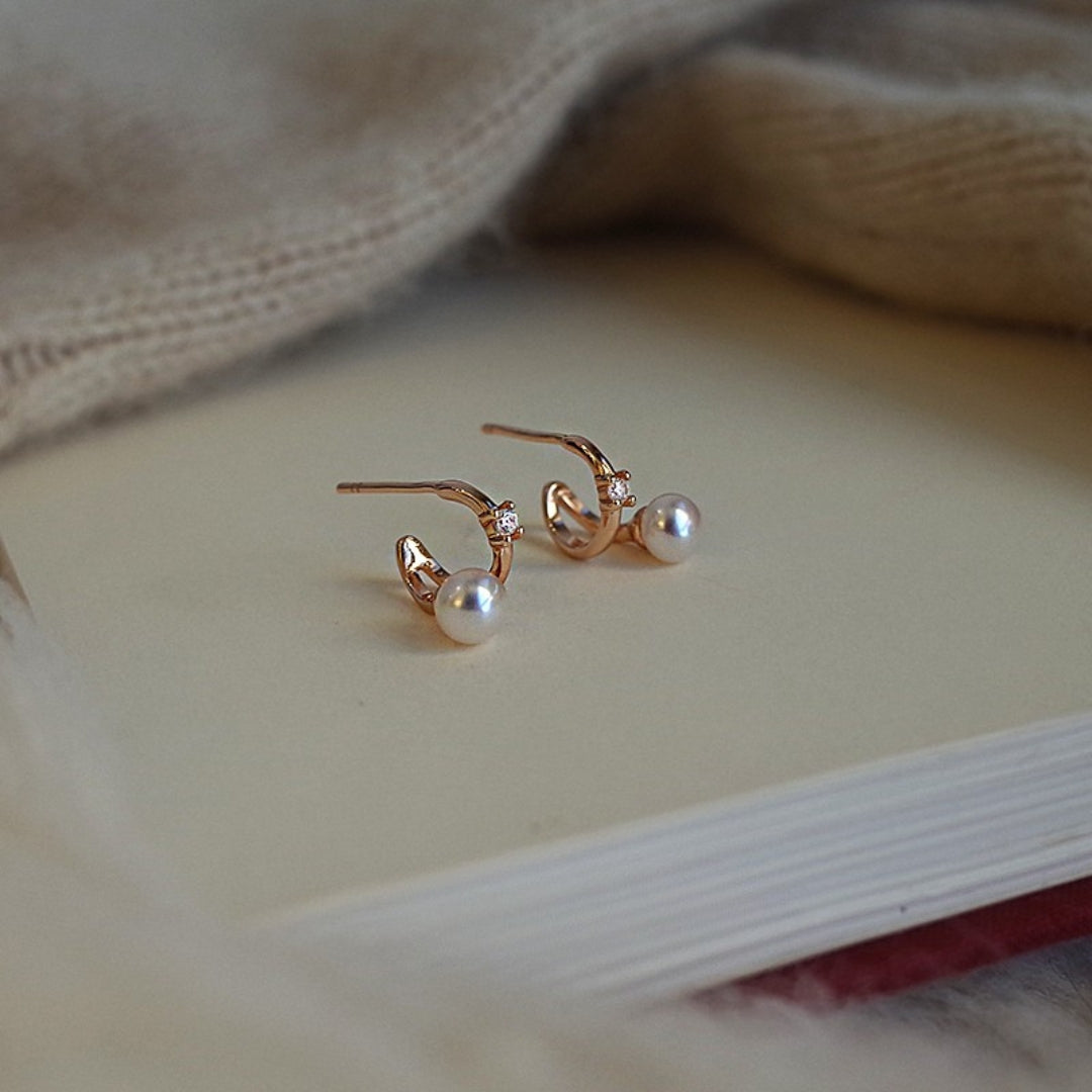 Pair of diamond huggies earrings on a light surface with a soft focus background