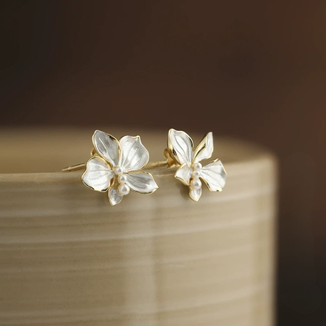 Silver flower-shaped earrings on a wooden surface with a blurred background
