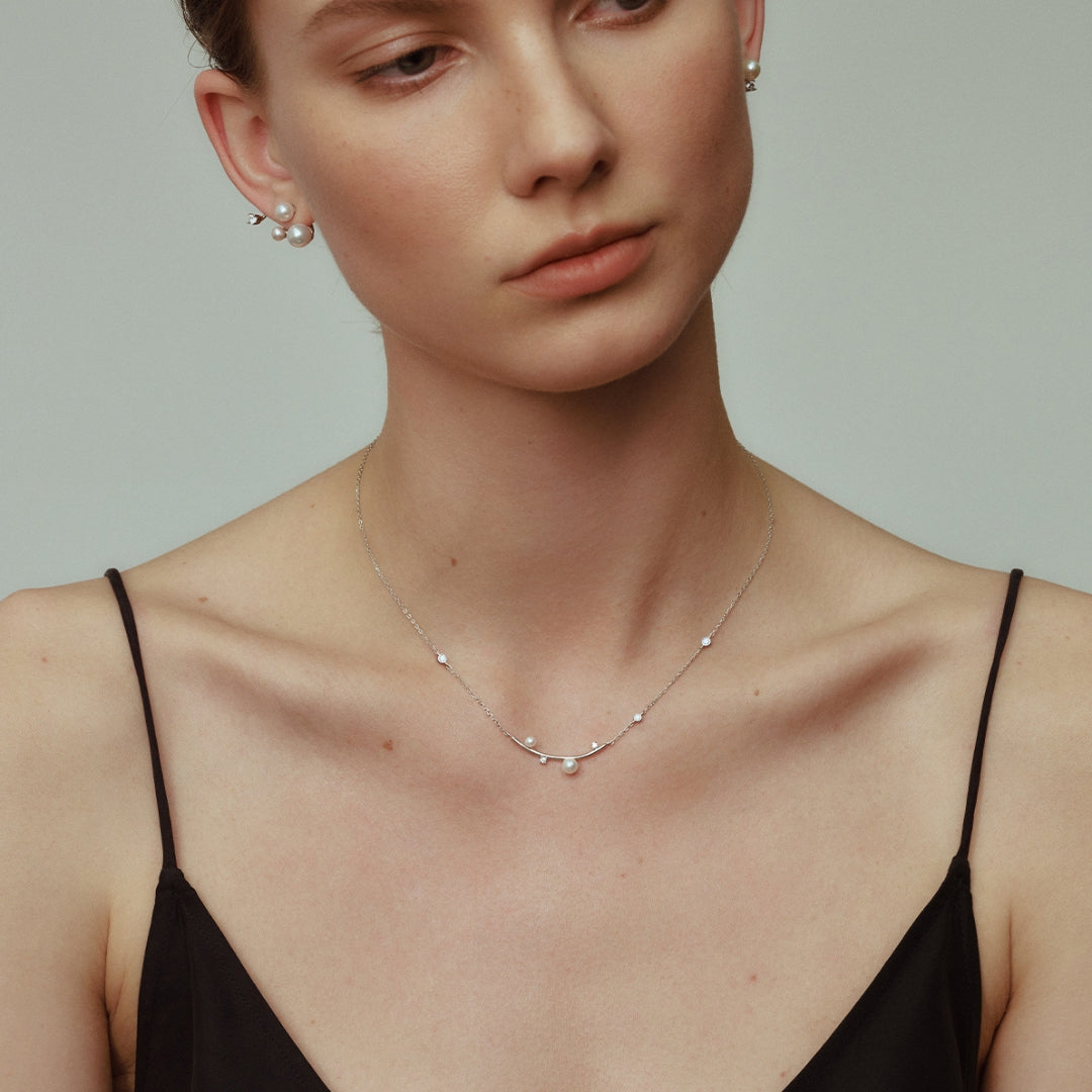 A floating diamond and pearl necklace worn by a woman.