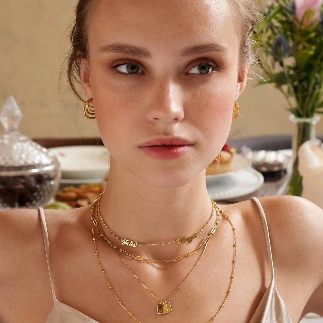 Modern minimalist style featuring a gold-plated custom name necklace on a model, ideal for everyday chic jewelry layering.