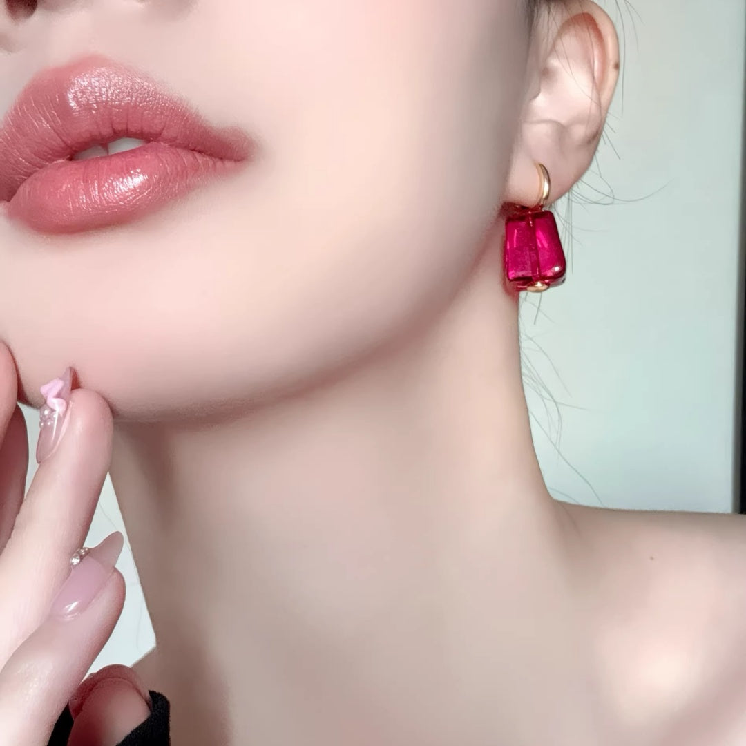 Close-up of a model wearing the magenta glass cube earring for style reference.