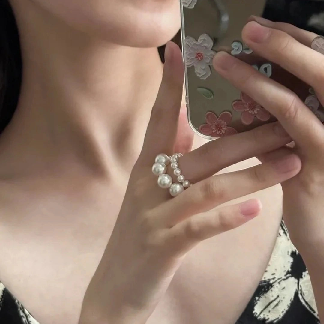 Model wearing two stacked Swarovski pearl elastic rings while holding a phone.