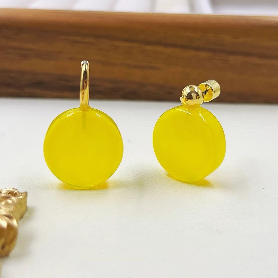 Side by side comparison of bright yellow glass hoop and stud earrings with 18K gold plating.